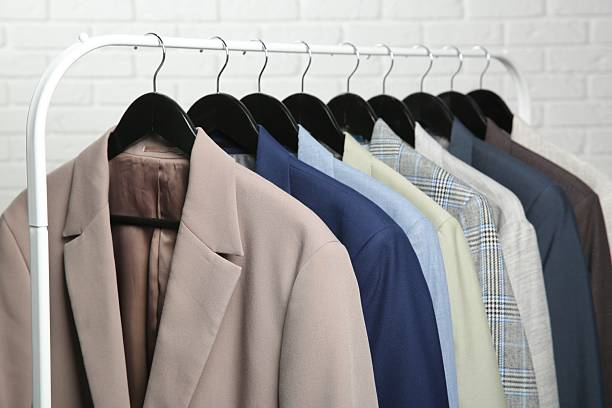 istock Dry-cleaning service. Many different clothes hanging on rack against white background, closeup 2253059793