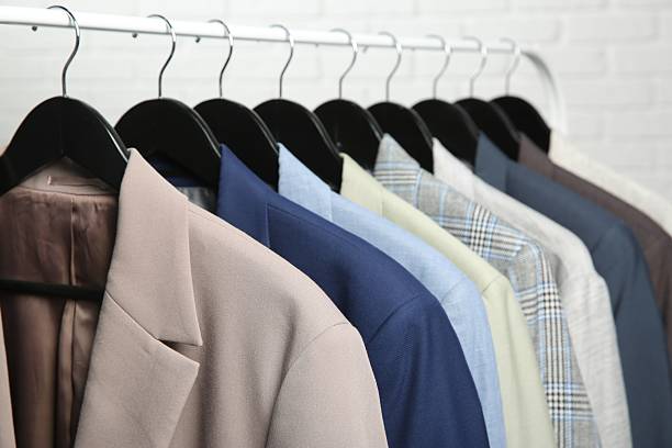 istock Dry-cleaning service. Many different clothes hanging on rack against white background, closeup 2253059829