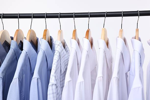 istock Dry-cleaning service. Many different clothes hanging on rack against white background, closeup 2253059839