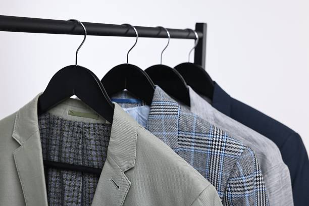 istock Dry-cleaning service. Many different clothes hanging on rack against white background, closeup 2253059870