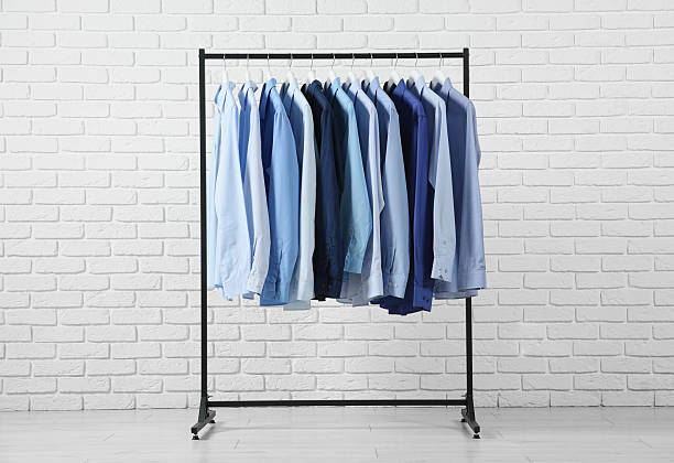 istock Dry-cleaning service. Many different clothes hanging on rack near white brick wall 2253059889