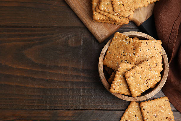 istock Cereal crackers with flax and sesame seeds on wooden table, flat lay. Space for text 2253060963