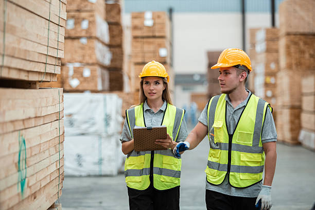 istock Team engineer carpenter wearing safety uniform and hard hat working holding clipboard checking quality of wooden products at workshop manufacturing. man and woman worker wood warehouse industry. 2253063783