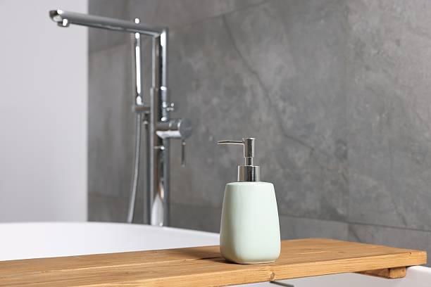 istock Bath accessory. Liquid soap dispenser on tub in bathroom 2253063953