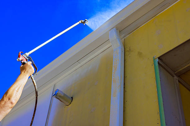 istock Worker spraying exterior paint on house using spray gun 2253067820