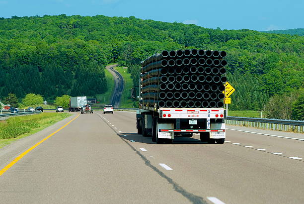 Garrett County, Maryland, USA - June 4, 2023: A tractor-trailer carrying pipes travels on Interstate 68 through the mountains of Western Maryland.