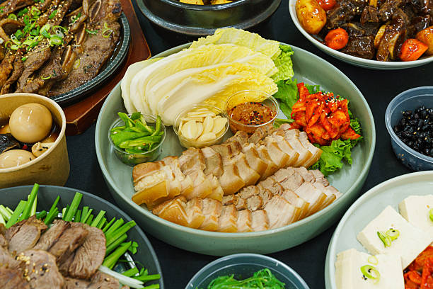 A vibrant spread of traditional Korean dishes featuring an array of colorful plates filled with iconic items against wooden table background.