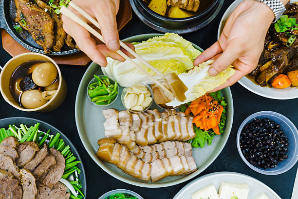 Table full of Koran food and person eating Pork Suyuk.