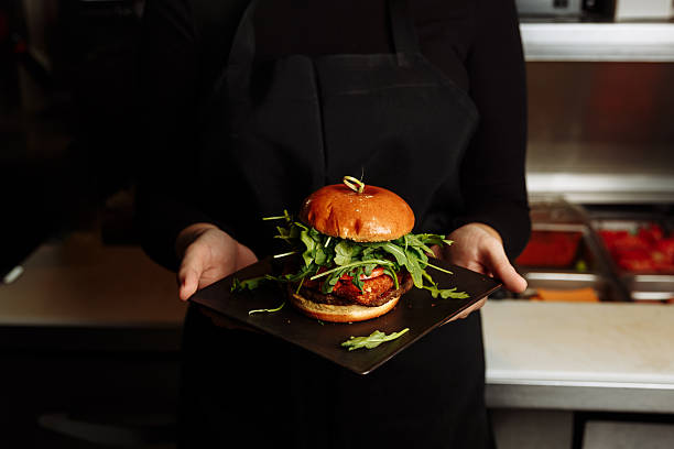 istock Chef hands in gloves assembling vegan burger with plant based patty and fresh arugula in restaurant kitchen. g 2253069873
