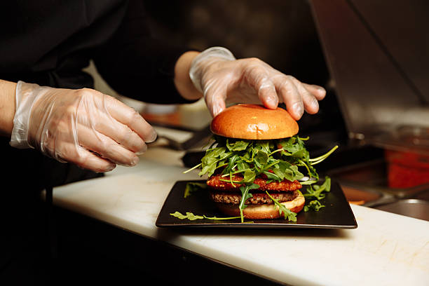 istock Chef hands in gloves assembling vegan burger with plant based patty and fresh arugula in restaurant kitchen. g 2253070037
