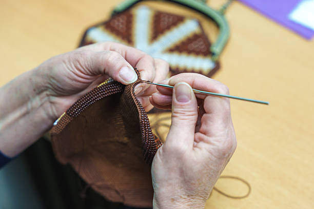 Hands of an artisan using a crochet hook to create a beaded pattern for a handmade bag. High quality photo