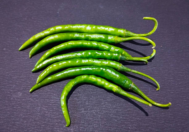 istock Seven fresh green chili peppers on dark 2253074818