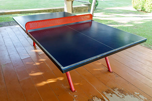 A black and red ping pong table. The table is on a wooden deck