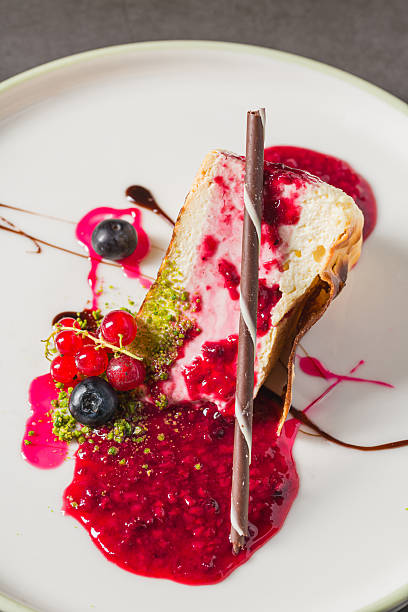 Cheesecake slice topped with fresh berries and vibrant sauce