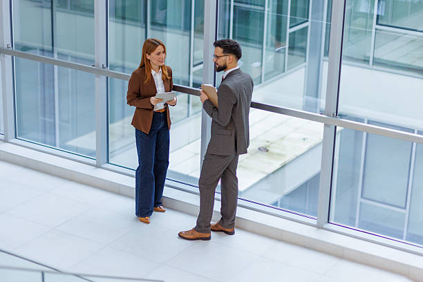 istock Business colleagues talking in modern office lobby 2253080601
