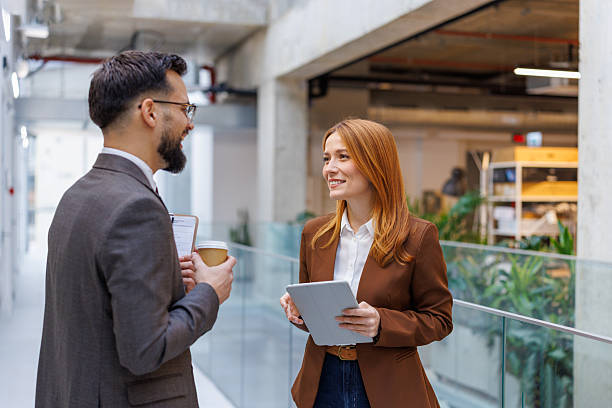 istock Business colleagues discussing project while standing in modern office corridor 2253080646