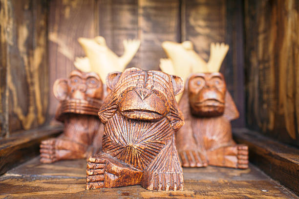 Kazakhstan, Almaty - June 26, 2025: Hand carved wooden sculptures of squirrels on tree trunks in a lush green park with coniferous trees.