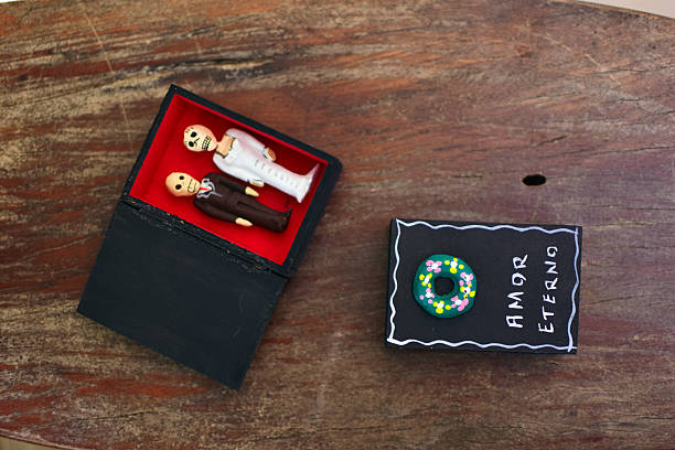 Miniature skeleton figures representing a bride and groom lie inside a matchbox with amor eterno written on it