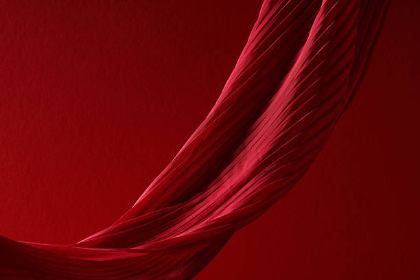 Elegant red silk fabric with diagonal pleated folds on a red textured background.