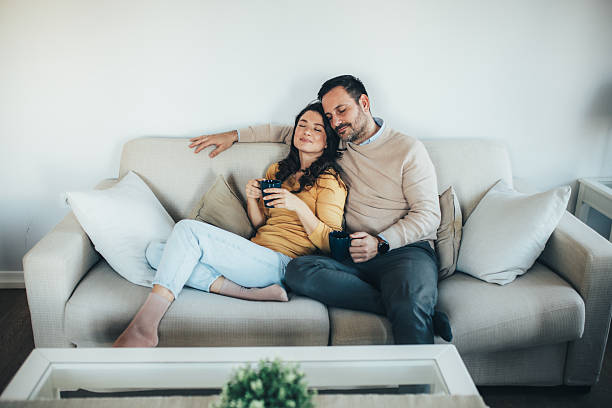 istock Happy couple relaxing together on a couch in a bright comfortable home 2253086864