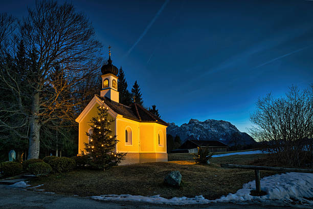 istock Illuminated chapel and decorated Christmas tree at dusk in winter landscape 2253088698