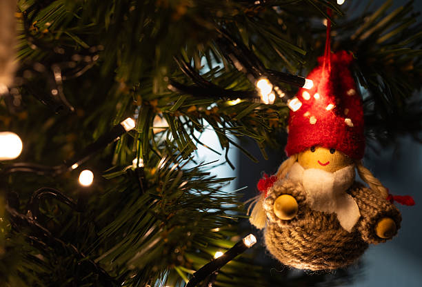 Close-up of a handmade Christmas gnome ornament hanging on a decorated tree with warm fairy lights, creating a cozy and festive holiday atmosphere.
