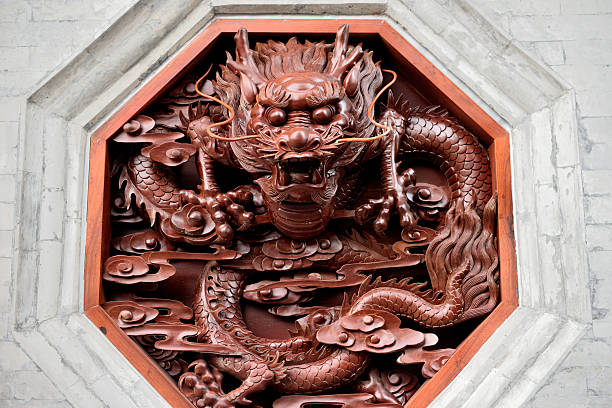 A detailed wooden carving of a dragon, featuring intricate scales and fierce expression, surrounded by swirling clouds, set in an octagonal frame