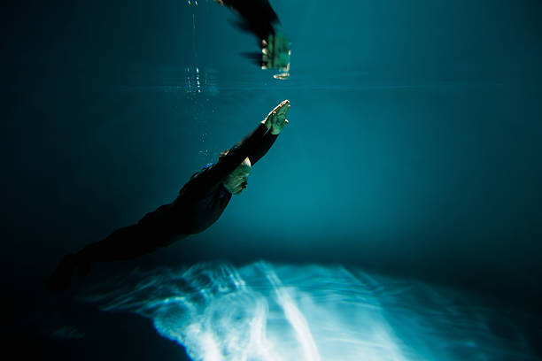 Side view of senior diver with nose clip training underwater in pool