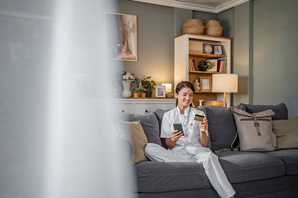 istock Female nurse shopping online using credit card on sofa 2253096936