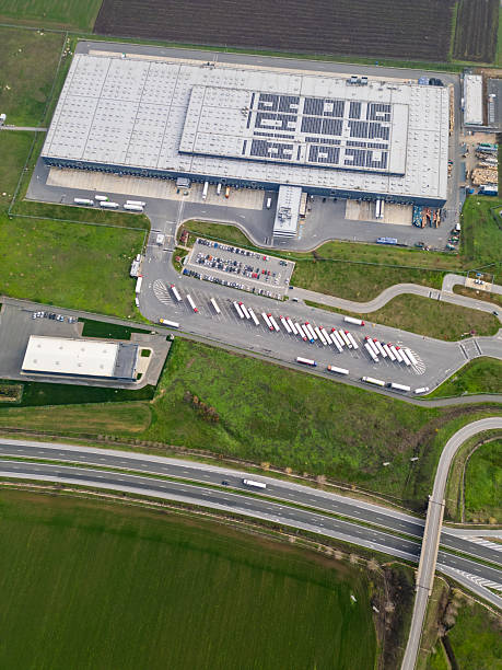 istock Aerial view of a large logistics warehouse with loading docks and trucks, distribution center surrounded by farmland. Supply chain and transportation concept 2253103874