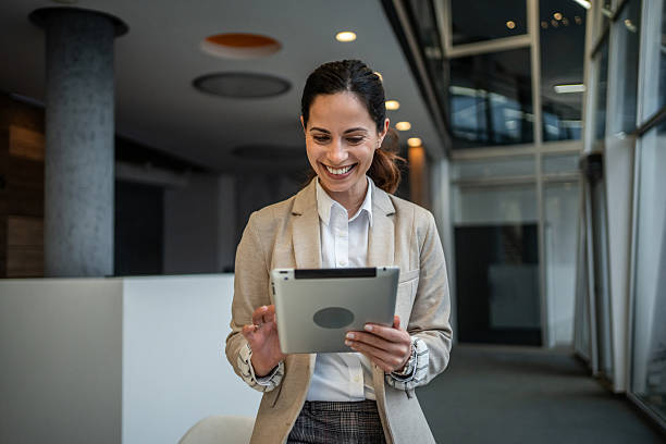 istock Businesswoman standing in office corridor using digital tablet 2253104371