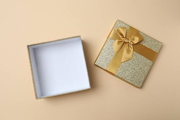 istock Open gift box with golden bow on color background, top view 2253106559