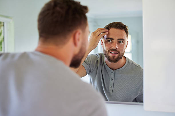 istock Man adjusting and checking hair in bathroom mirror 2253106759
