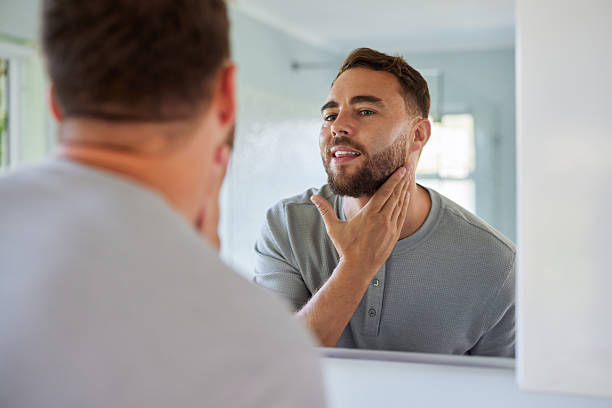 istock Mid adult man checking beard in mirror 2253106823