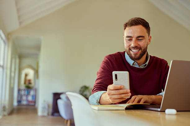 istock Mid adult man in casual outfit using phone while working from home 2253109926