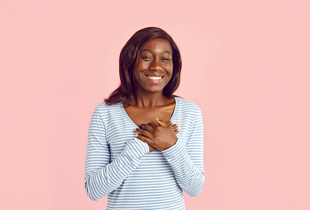 istock African american woman standing with her hands on chest with grateful face expression. 2253110642