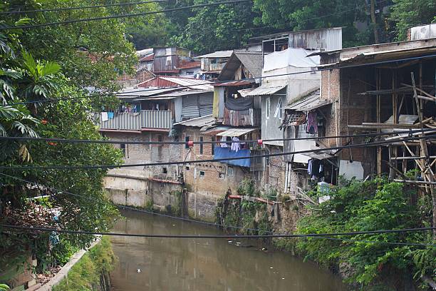 istock Dense Riverside Settlement with Murky Canal and Makeshift Housing Structures 2253111633