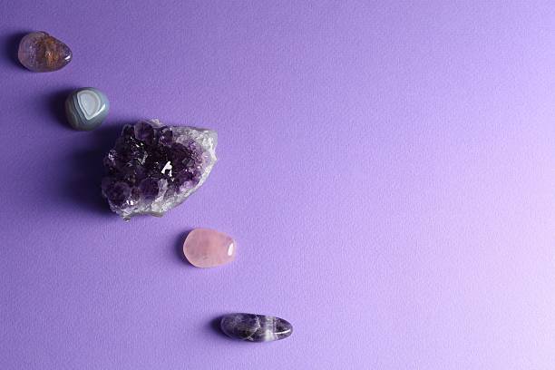 Different beautiful gemstones on purple background, flat lay. Space for text