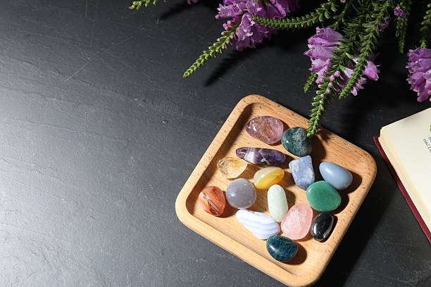 istock Different beautiful gemstones, book and flowers on black table, flat lay. Space for text 2253114661