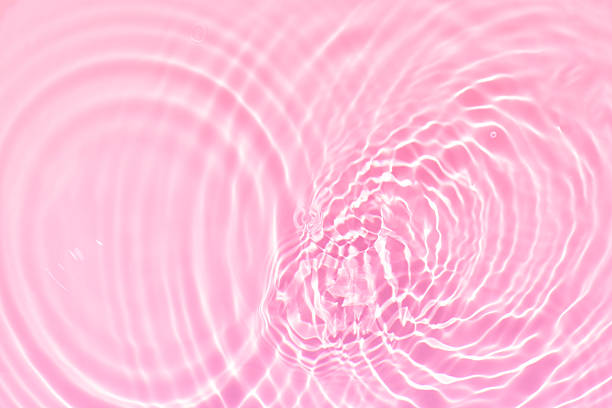istock Pink water bubbles on the surface ripples. Defocus blurred transparent pink colored clear calm water surface texture with splash and bubbles. Water waves with shining pattern texture background 2253115843