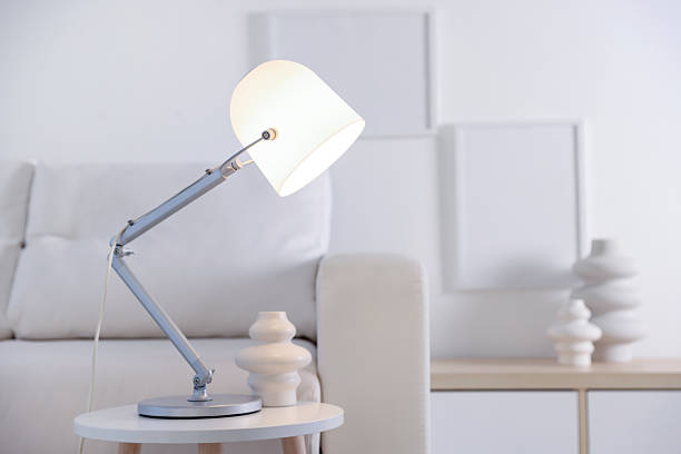 Stylish lamp and vase on table near sofa indoors, space for text
