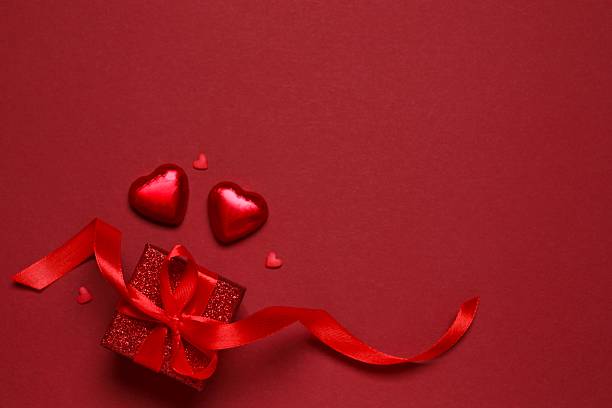 istock Gift box with red hearts on color background 2253117589