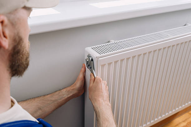 istock Man performing maintenance on a radiator in a modern apartment heating system 2253117921