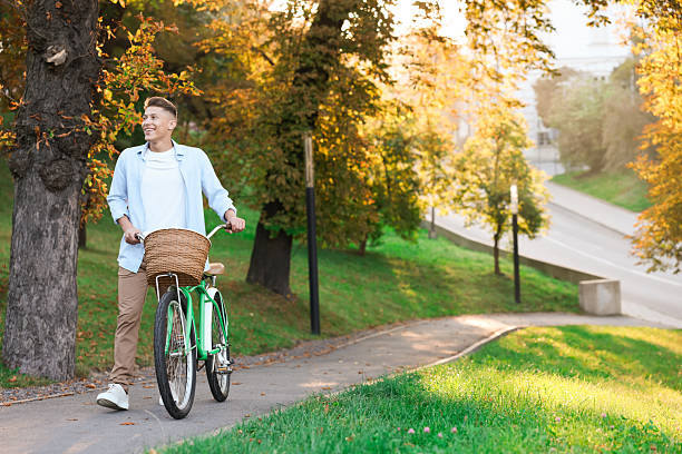 istock Happy man walking his bicycle in park on sunny day. Space for text 2253117927