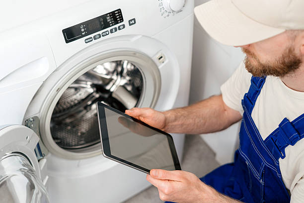 istock Repairing a washing machine at home by a technician with a tablet in hand 2253118066