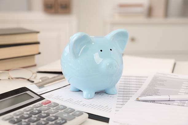 istock Piggy bank, calculator and paperwork on white table indoors 2253118885