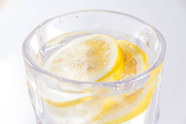Clear glass filled with water and lemon slices, refreshing beverage associated with hydration and health.