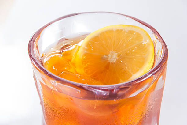 A clear glass of iced tea with a fresh lemon slice floating on top, bright and chilled.