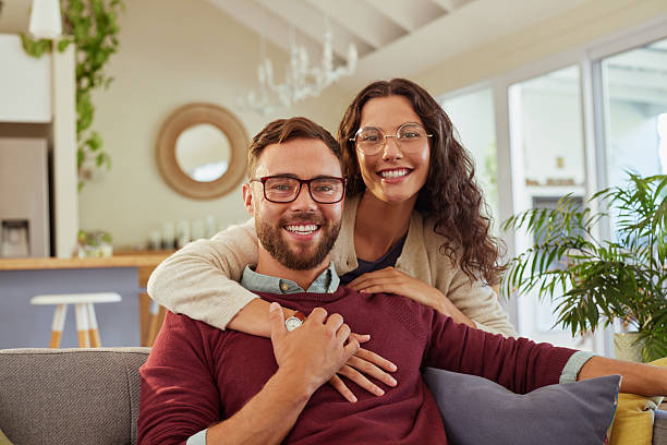 Beautiful couple hugging at home while wearing eyeglasses and smiling