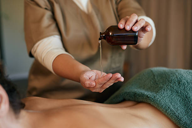 istock Masseuse applying oil massage on woman's back 2253120717
